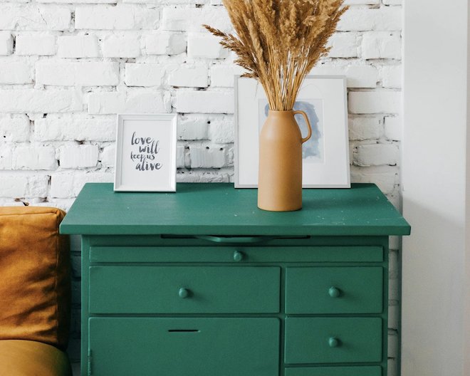 Green furniture with some portrais and flowers as decoration over it.